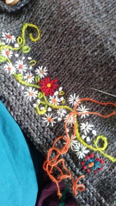 a close up of a sweater with flowers on it and some needles in the middle