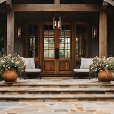 two chairs sitting on the front steps of a house with flowers in large planters