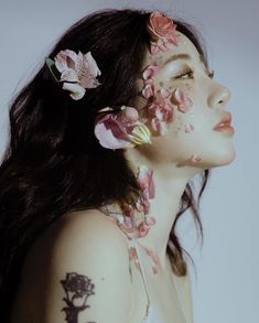 a woman with flowers painted on her face and body is looking up at the sky