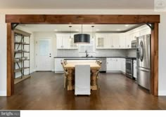 an open kitchen and dining room with white cabinets, stainless steel appliances and wood flooring