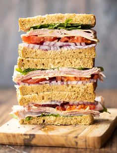 a stack of sandwiches sitting on top of a wooden cutting board