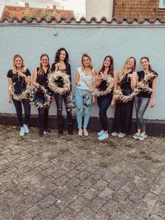 a group of women standing next to each other holding wreaths