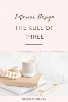 a book, candle and other items sitting on top of a table with the words interior design the rules of three