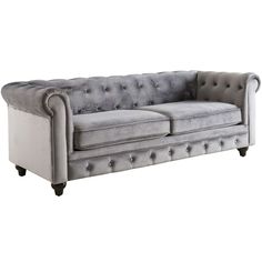 a grey velvet chesterfield style sofa with buttons and tuftings on the armrests