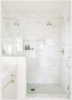 a white tiled bathroom with shower and sink