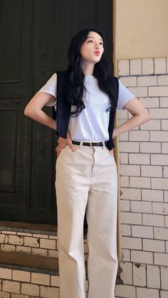 a woman standing in front of a brick wall with her hands on her hips and looking up