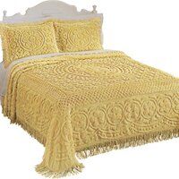 a bed with yellow bedspread and white headboard