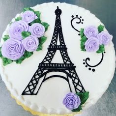 a cake decorated with purple roses and the eiffel tower