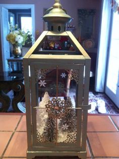 a lantern with snowflakes and pine cones on the top is sitting on a tile floor