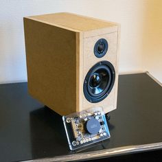 an electronic device sitting on top of a table next to a box with speakers in it