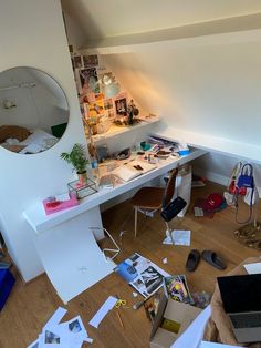 a messy room with lots of clutter on the floor and a desk in the corner