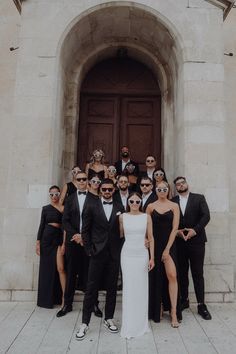 a group of people standing in front of a door wearing black and white outfits with sunglasses on