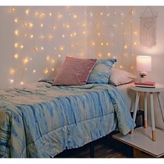 a bed with blue and white bedspread next to a table with a lamp on it