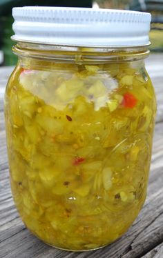 a jar filled with pickles sitting on top of a wooden table