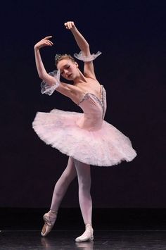 a ballerina in pink tutu and tiara with her arms stretched out to the side