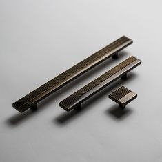 three pieces of metal sitting next to each other on a white surface with no one in it