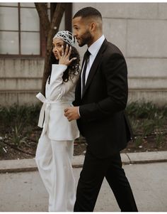 a man in a suit and tie walking next to a woman wearing a headdress