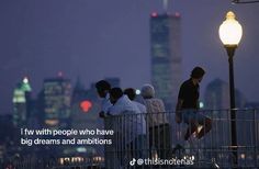 some people are standing on a bridge and looking at the city lights in the distance