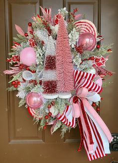 a christmas wreath hanging on the front door with pink and red ornaments around it,