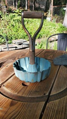 an outdoor table with a blue bowl on it and a metal candle holder in the middle