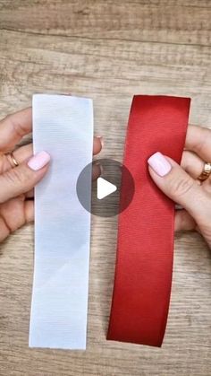 two hands holding red and white ribbon on top of a wooden table next to each other