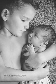 a black and white photo of a woman holding a baby in her arms while she is breastfeeding