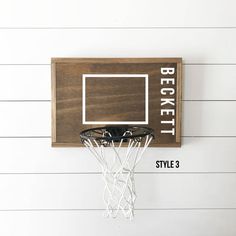 a basketball hoop mounted to the side of a white wall next to a wooden sign