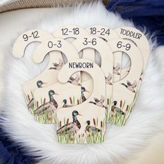 three wooden numbers with ducks on them sitting next to some white fur and blue fabric