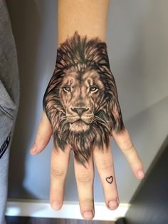 a person's hand with a lion tattoo on it and a heart in the middle