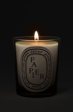 a candle that is lit up with the words paer on it in front of a black background