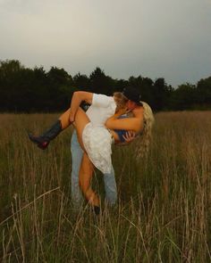 a man and woman are hugging in the middle of a field