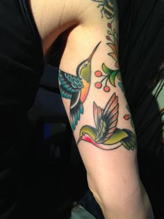 a woman's arm with colorful birds and flowers on it