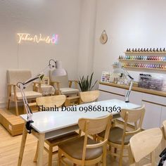 the interior of a nail salon with wooden chairs and desks, lighted by neon signs