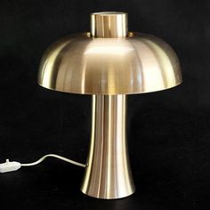 a gold colored table lamp with a white cord plugged in to it's base