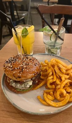 a hamburger and fries are on a plate with a glass of lemonade in the background