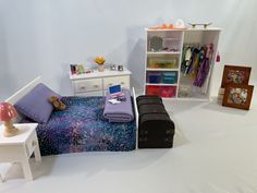 a doll house bedroom with white furniture and purple bedding, including a small chest of drawers