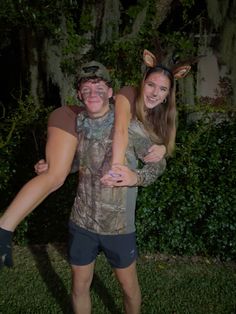 a man carrying a woman on his back in front of some trees and bushes at night