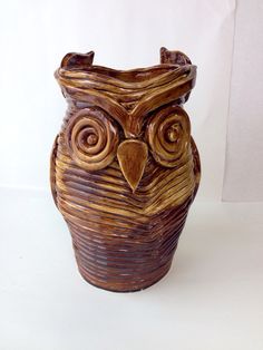 an owl shaped vase is sitting on a white surface