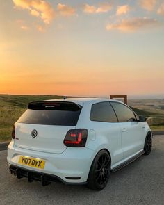 a white vw golf gtr parked on the side of a road at sunset