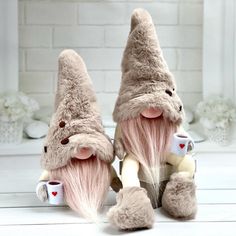 two stuffed gnomes with pink hair and coffee cups on their feet, sitting next to each other