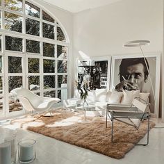 a living room with white furniture and large windows on the wall, along with an area rug that looks like sheepskin