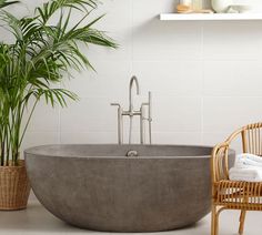 a bathtub sitting next to a chair and potted plant in a room with white walls