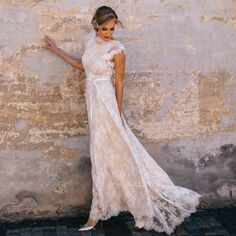 a woman in a white dress leaning against a wall