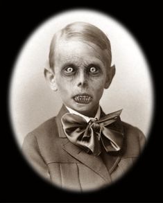 an old black and white photo of a young boy wearing a suit with a bow tie