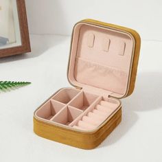 an open wooden jewelry box sitting on top of a white table next to a mirror