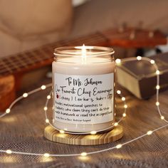 a white candle sitting on top of a table next to a string of lights and a guitar