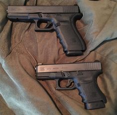 two handguns are laying on a bed with the covers pulled back to reveal them