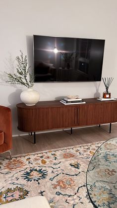 a flat screen tv mounted to the side of a wooden cabinet in a living room