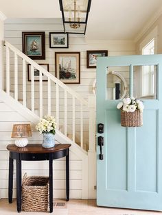 a blue door and some pictures on the wall next to a table with flowers in it