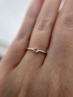 a woman's hand with a diamond ring on top of her finger, wearing a gold band